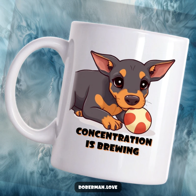Funny Doberman Mug featuring a kawaii doberman puppy concentrating hard while trying to balance a small ball on its snout.