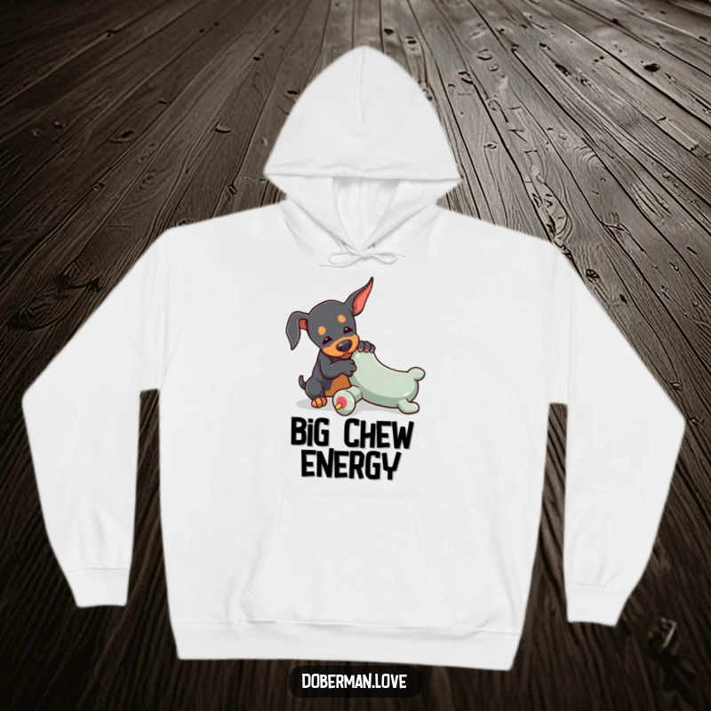Funny Doberman hoodie featuring a tiny dog playfully wrestling with an oversized toy chew, offering warmth and endearing humor.