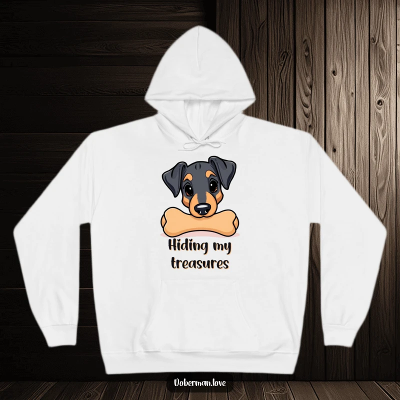 Funny Kawaii Doberman hoodie; a playful dog peeks from behind a large chew toy, ready for cuddles and laughs.
