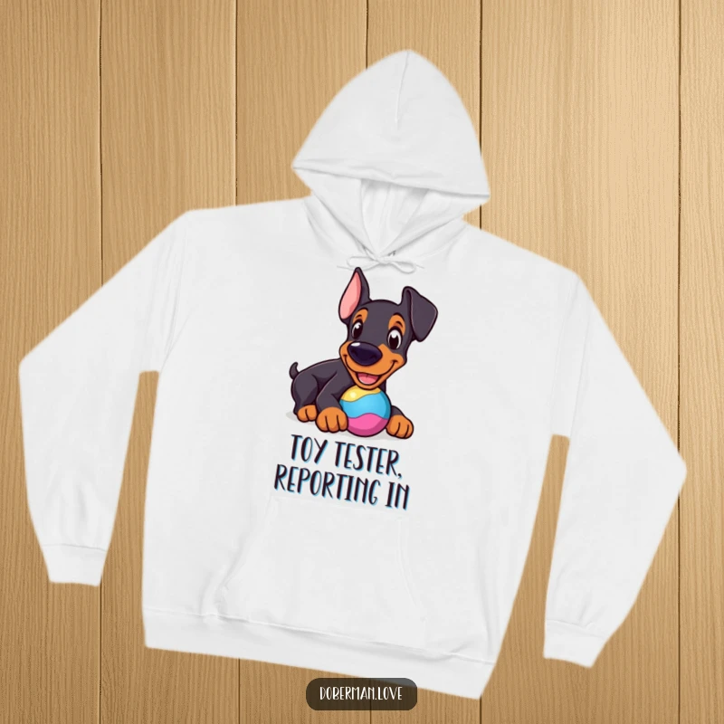 Funny Doberman Hoodie: Cheerful dog nudging a colorful toy, cozy and humorous dog-themed apparel.