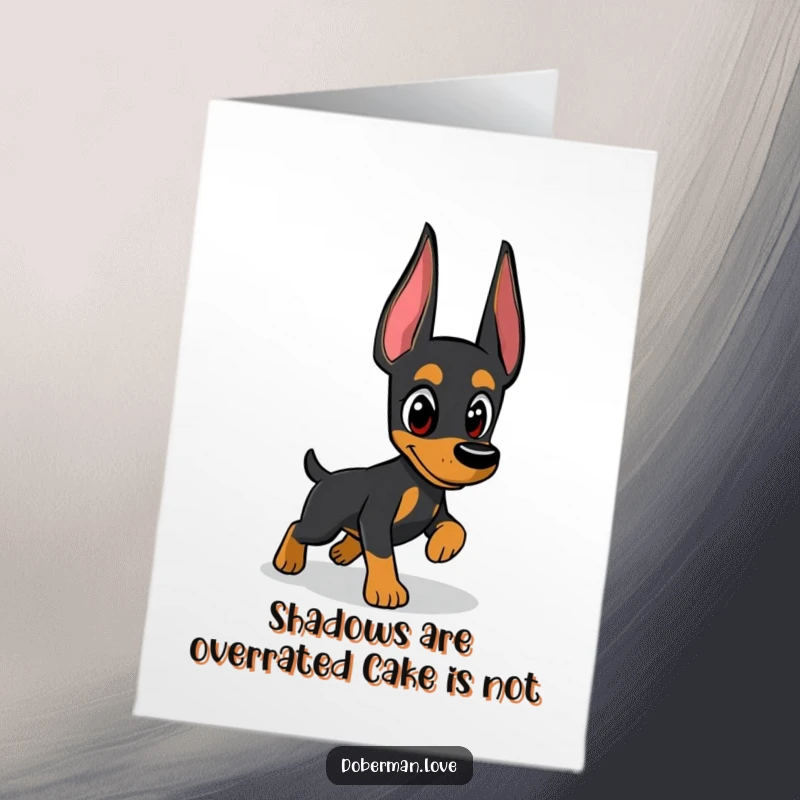 Funny free printable birthday card featuring a cute Doberman intently chasing its own shadow with wide, watchful eyes.
