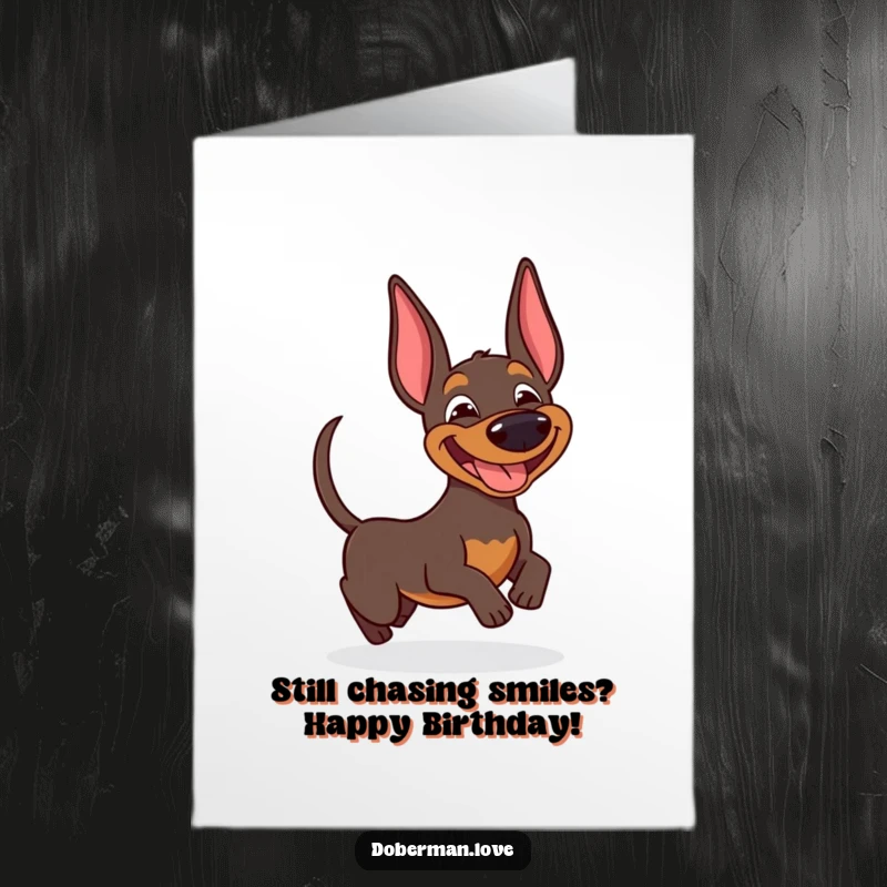 Funny Free Printable Birthday Card showing a happy doberman with a huge grin, gleefully spinning after its own wagging tail.