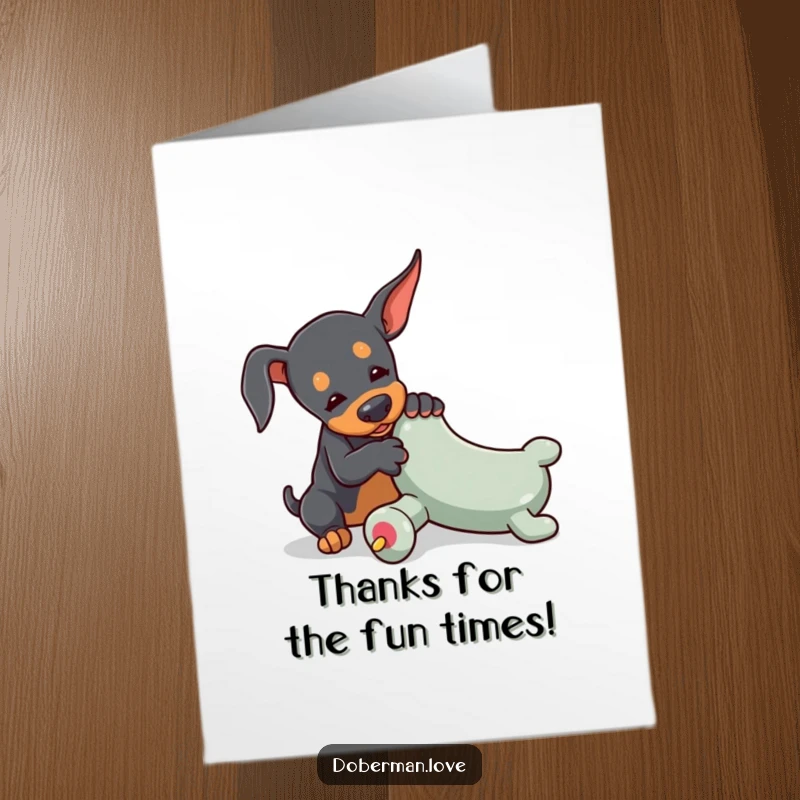 Free Printable Thank You Card: A tiny Doberman playfully wrestles with an oversized toy chew, sending big thanks.