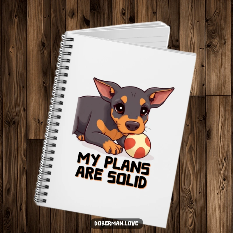 Funny Doberman Notebook showing a kawaii doberman puppy concentrating on balancing a ball on its snout, perfect for notes.