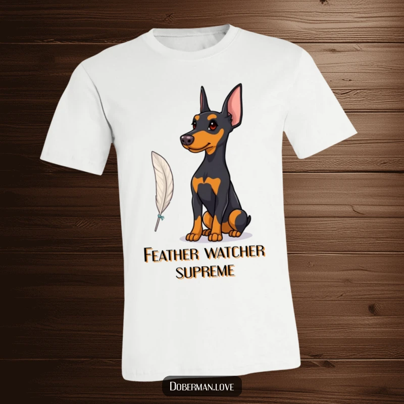 Funny T-Shirt featuring a Doberman with a proud stance, observing a fluttering feather, conveying a sense of regal contemplation.