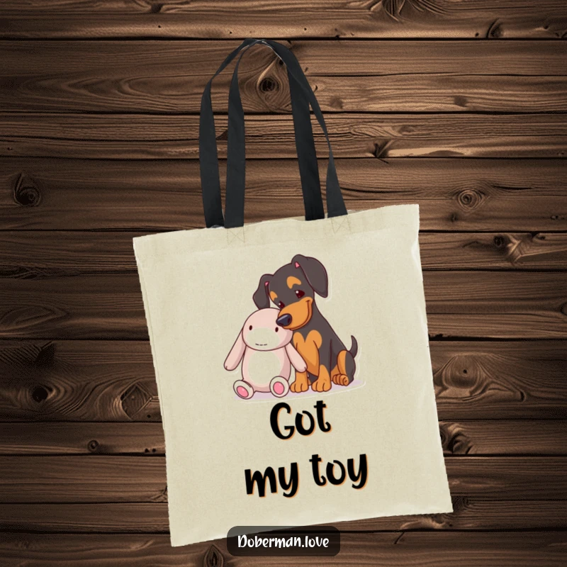 Funny Doberman nudging a plush toy on a durable tote bag, a practical and humorous accessory for dog moms.
